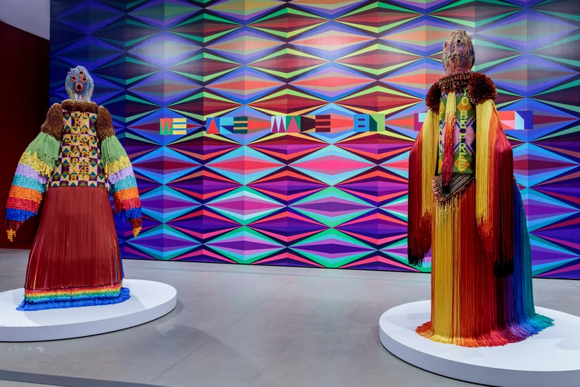 two multi-media human figure forms against a large multi-colored mural