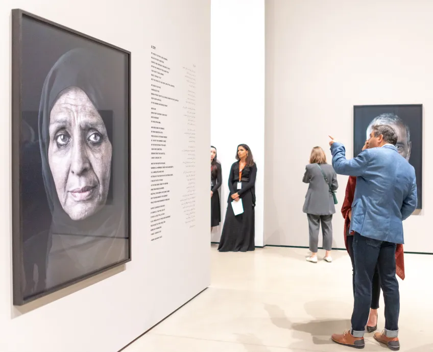 Photo of visitors looking at Shirin Neshat's work.