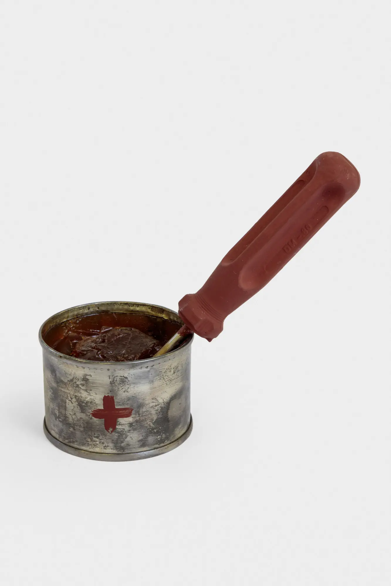 Tin can with a red cross on it and a screwdriver in the can with its base sticking out